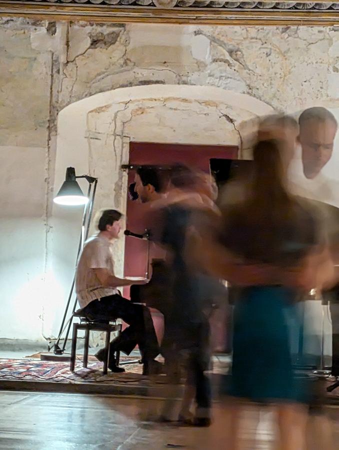 Dancers moving past a pianist in the palace ballroom